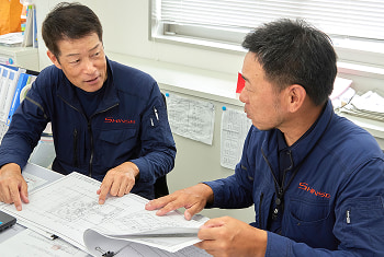 真生工業の職人らが解体工事現場の現地調査について話し合う様子