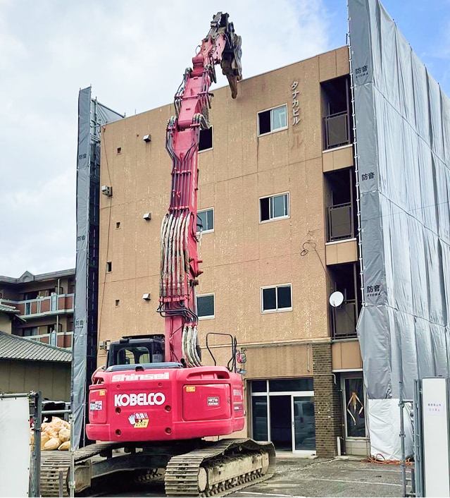真生工業の保有する大型解体重機が鉄骨造のビル（4階建てマンション）を解体しようとしている様子