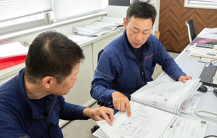 真生工業の職人らが解体工事現場の現地調査について話し合う様子